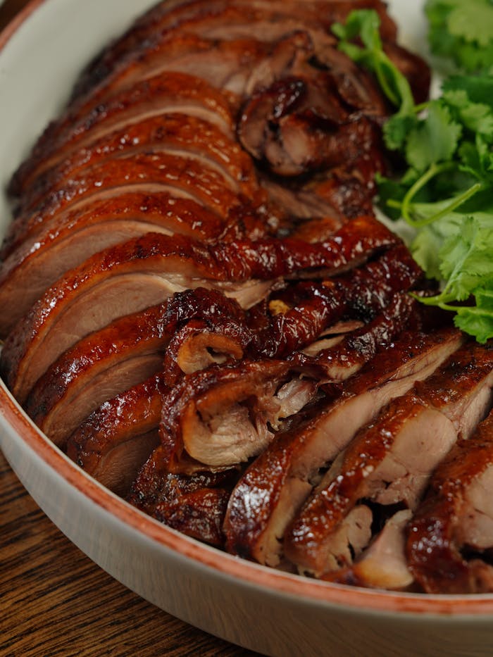 Close-up of juicy sliced roasted duck with herbs in a bowl, ready to serve.